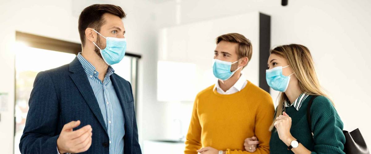 Young couple communicating with real estate agent while buying new home during coronavirus pandemic.