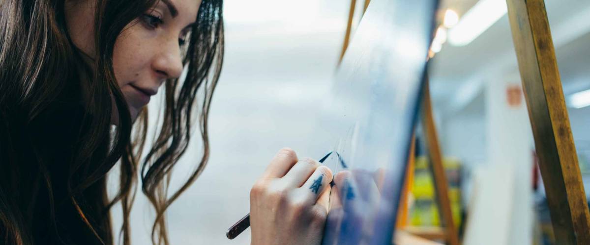 Close up portrait of beautiful and authentic young female artist or painter create art piece. Detailed work for personal creative project. Tattoo artist draws artwork
