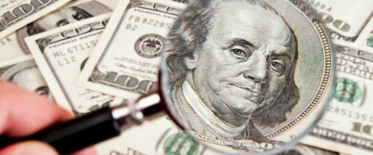 magnifying glass lies on american dollars on white