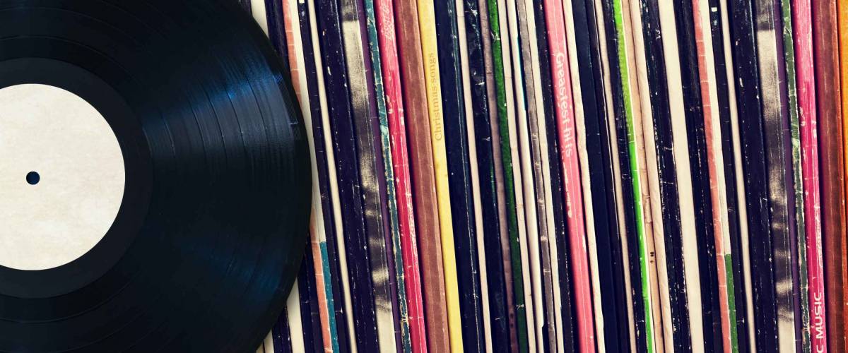 Vinyl record with copy space in front of a collection of albums (dummy titles), vintage process