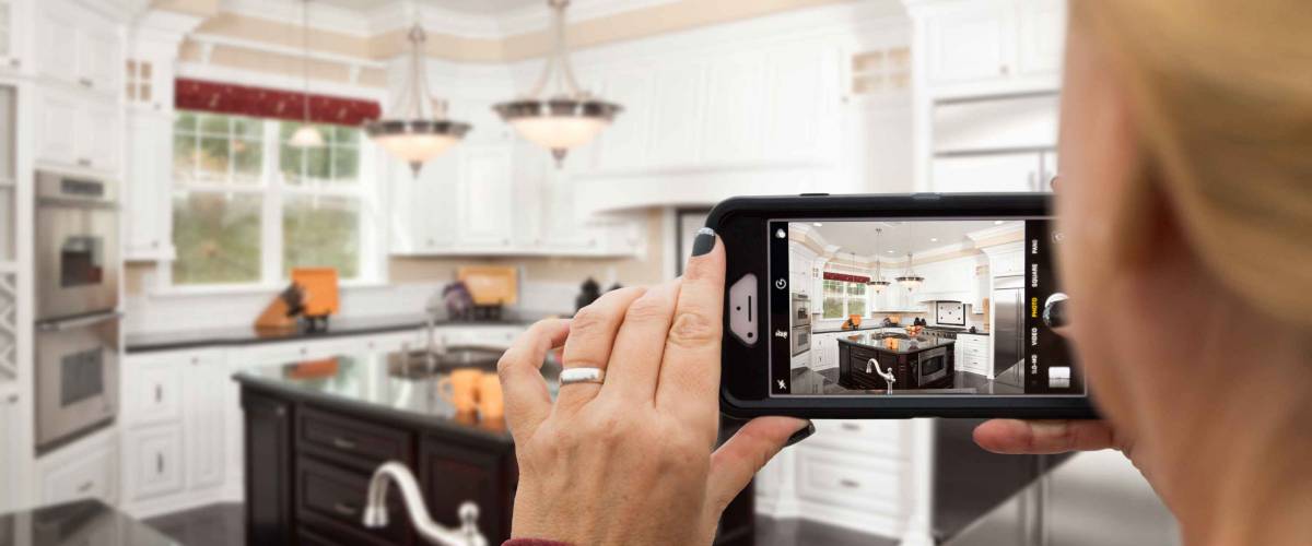 Woman Taking Pictures of A Custom Kitchen with Her Smart Phone.