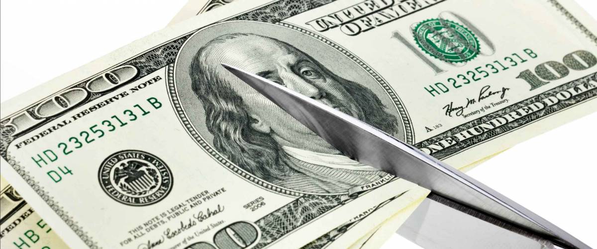 Business concept. Dollars are cutting with scissors on a white background.