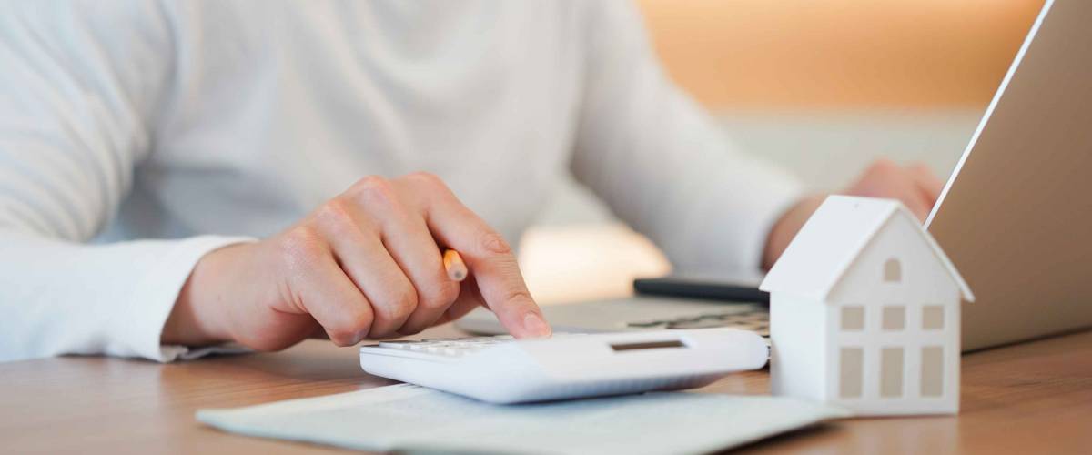 close up young man hand press on calculator to check and summary expense of home loan mortgage for refinance plan , people lifestyle concept