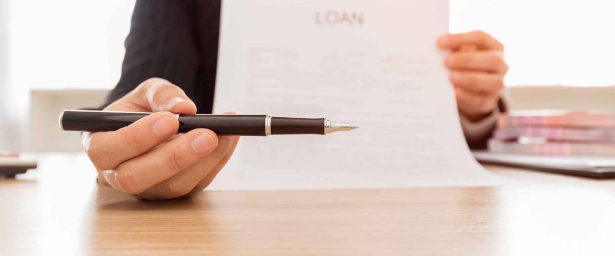 Close up of someone holding a pen and paper towards camera