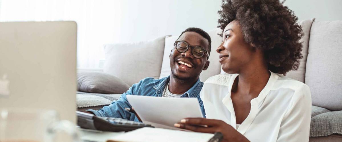 Young married couple doing their paperwork together, paying bills online.