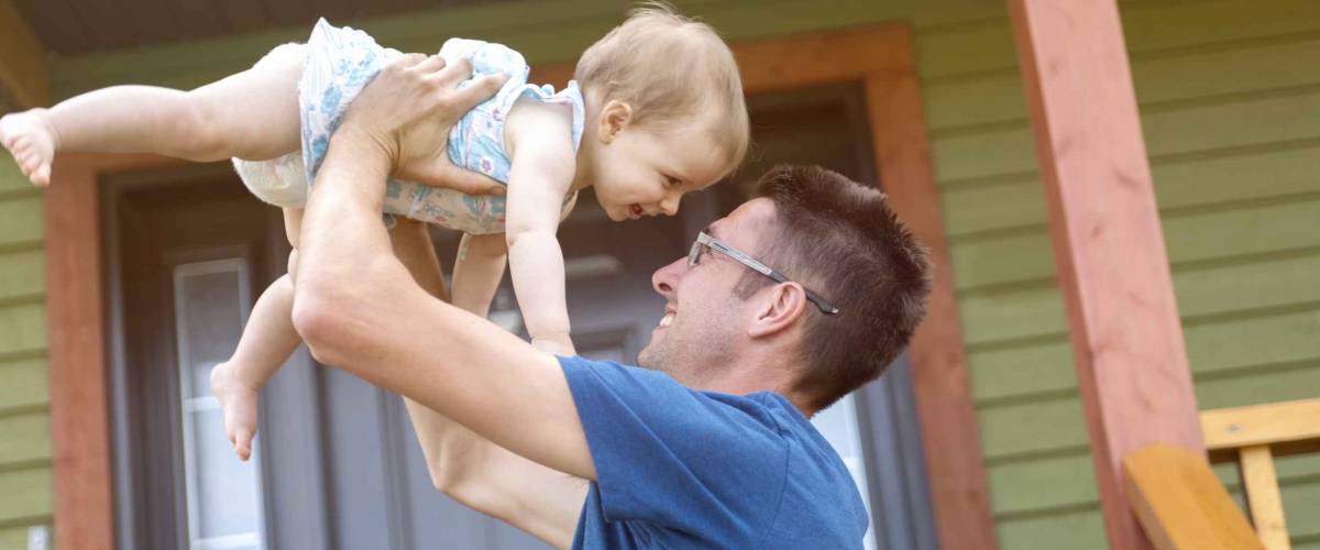 A father and daughter play in front of the house