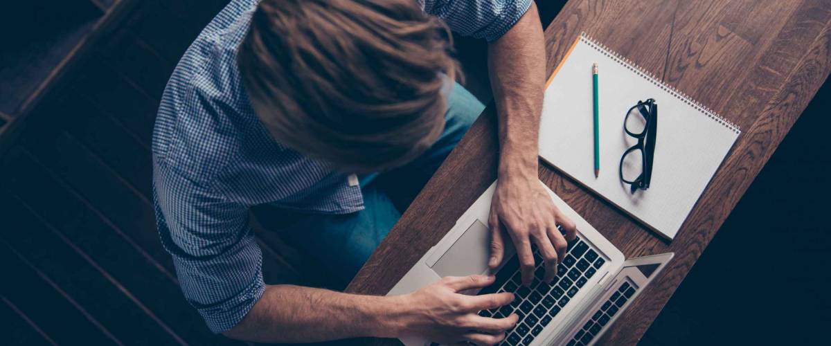 Top view of young busy worker typing on laptop
