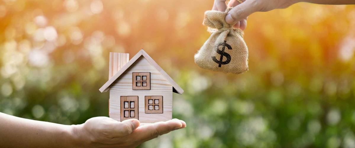 Money bag home and man hands in sunlight represent to exchange or saving money or investing to buy a home or loan to buy a house or real estate or investment for the future.