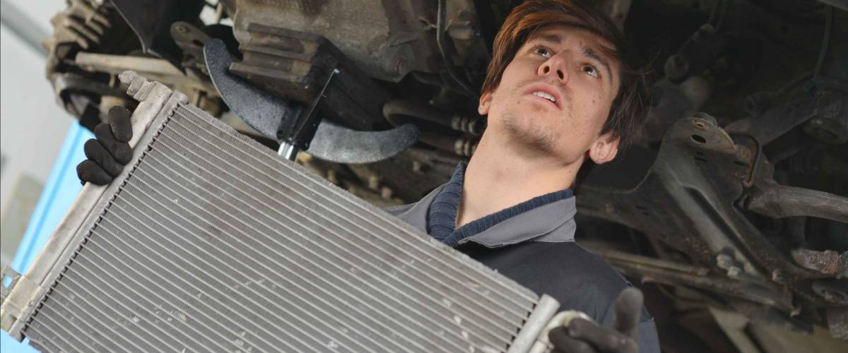 A mechanic replaces a radiator.