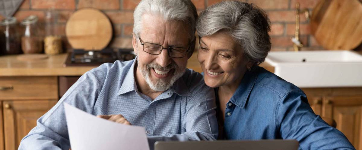 Happy elderly couple read documents at desk