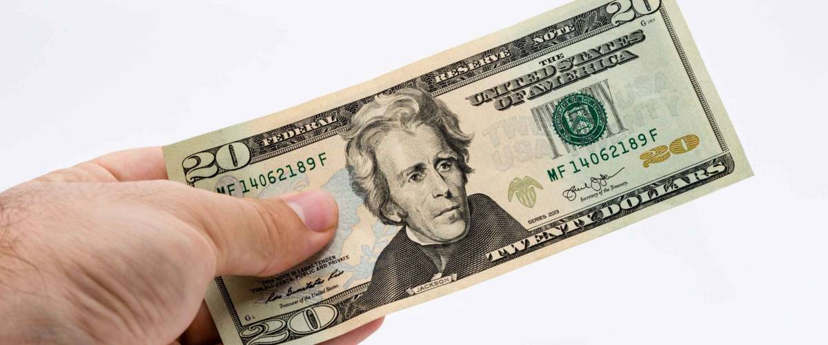 A Caucasian male hand holding a 20 dollar note. This image has a white background.