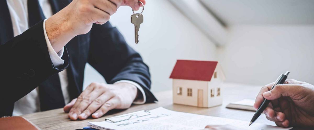 Estate agent giving house keys to client after signing agreement contract real estate with approved mortgage application form, concerning mortgage loan offer for and house insurance.