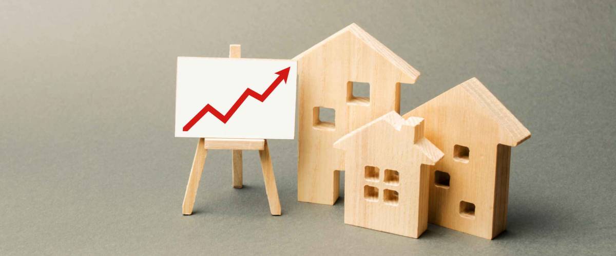 three wooden houses and a red up arrow on the sign. Real estate value increase. High rates of construction, high liquidity. Supply and demand. Rising prices for housing, building maintenance.