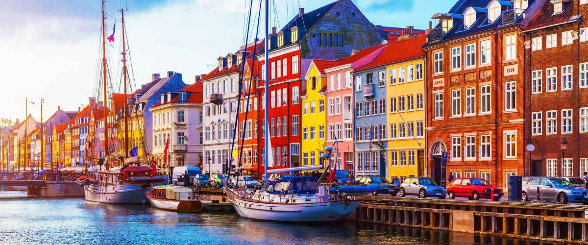 Scenic summer sunset view of Nyhavn pier with color buildings, ships, yachts and other boats in the Old Town of Copenhagen, Denmark