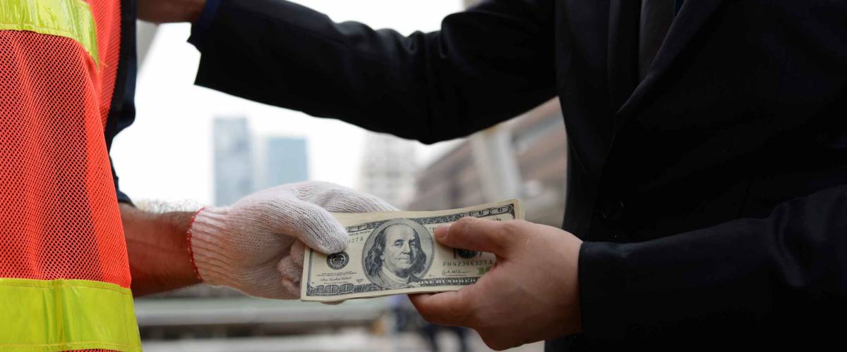Man paying a person in high-vis vest in cash