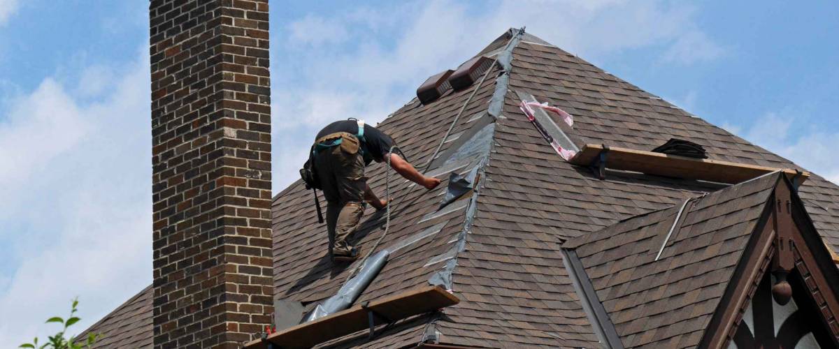 roofer at work repairing a steeply sloped shingle roof