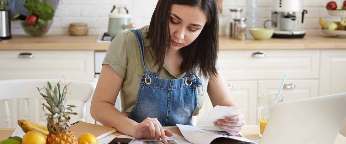 Young woman making a budget in front of laptop