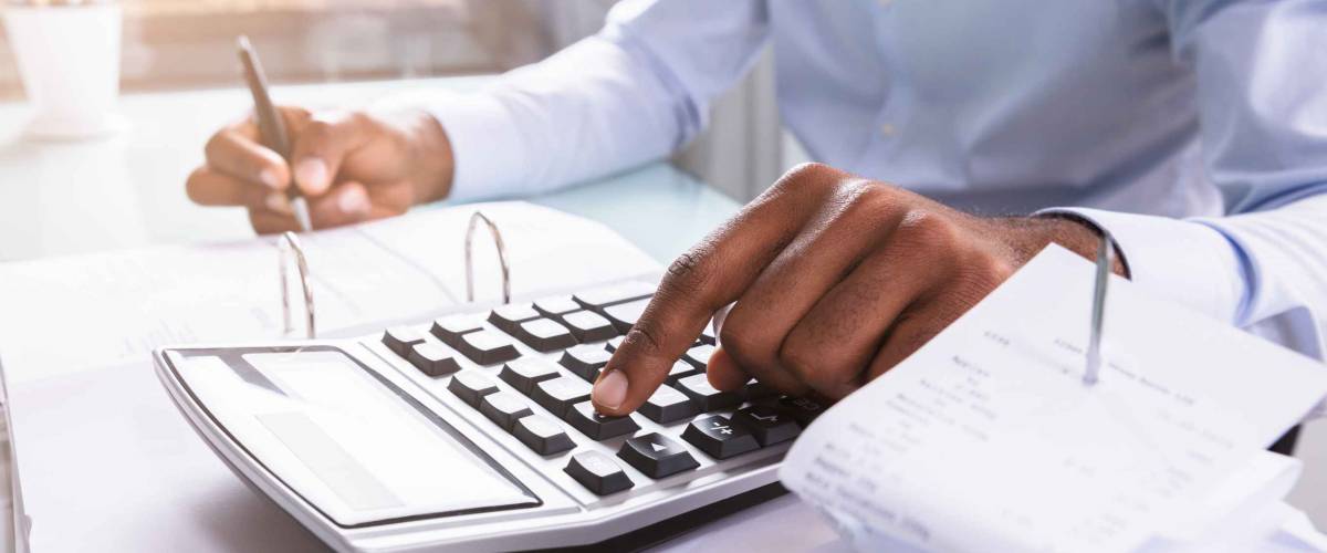 Close up of person using calculator while holding pen in other hand