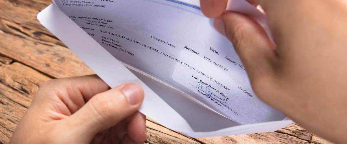 Cropped hands of person opening envelope with a check