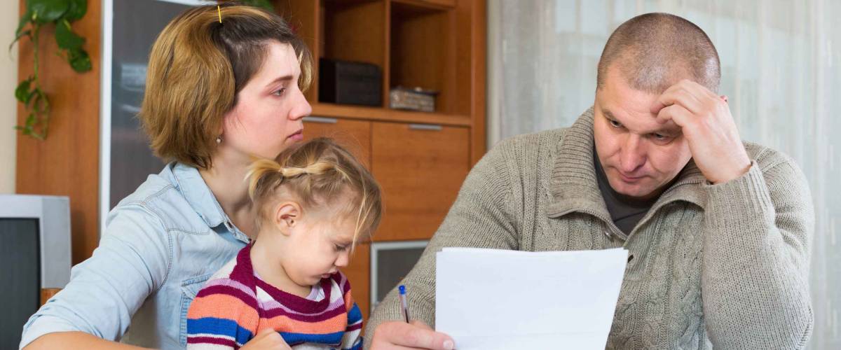 Serious couple with little girl counting budget at home