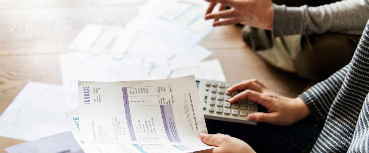 Close up of hands using calculator and holding bills