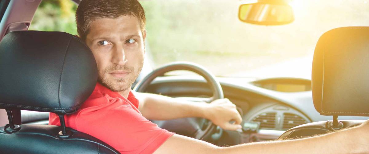 Handsome man driver looking back and parking car
