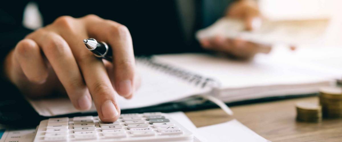Investors are calculating on calculator investment costs and holding cash notes in hand.