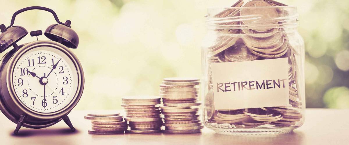 Hand putting Coins in glass jar with retro alarm clock for time to money saving for retirement concept , vintage retro color tone