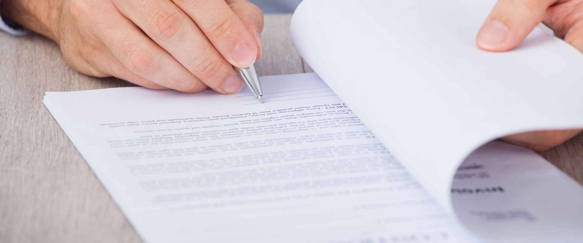 Cropped image of man signing a document at his desk