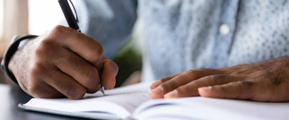 Close up of man's hands writing in a notebook