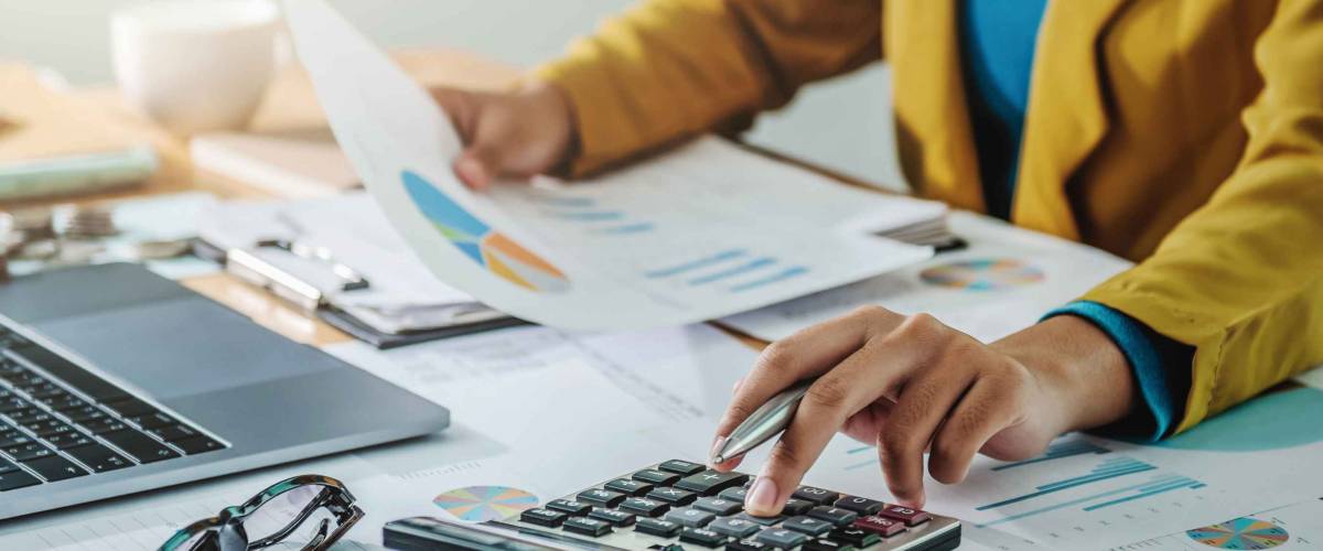 Close up of woman's hands looking at sheet with pie chart, using calculator