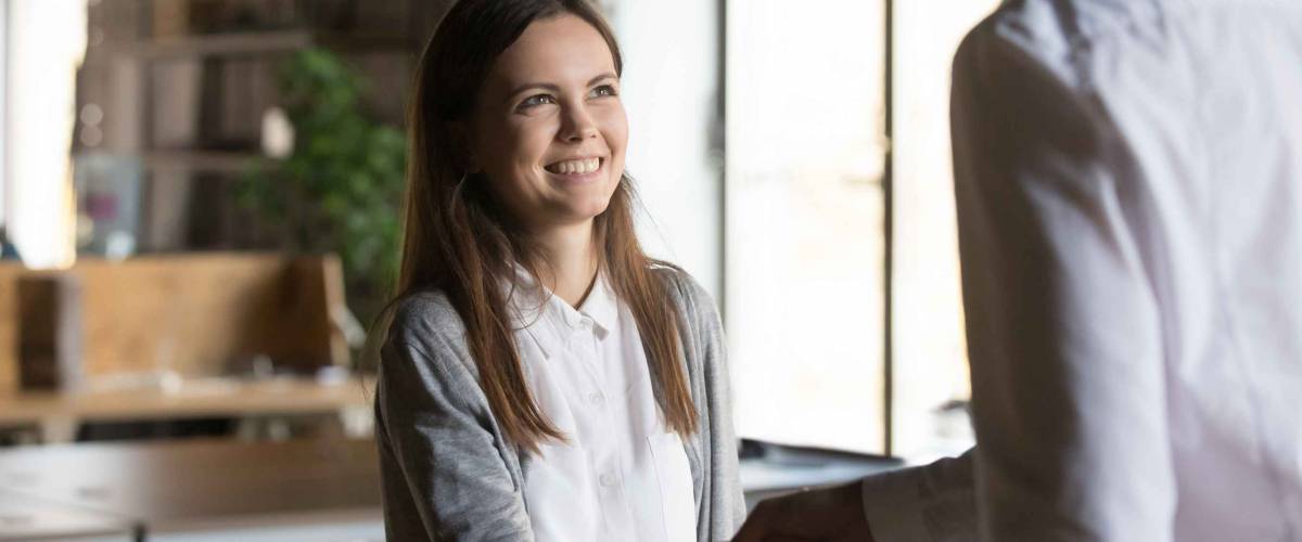 Excited girl shaking hands with someone in an office setting