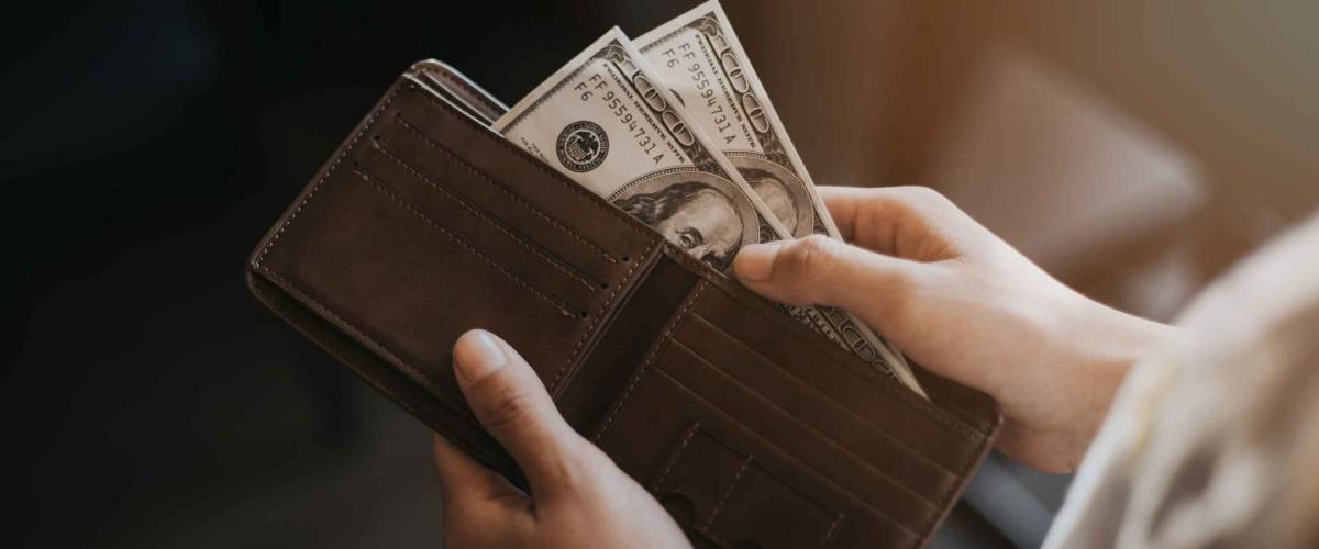Woman standing carrying a brown purse full of money.