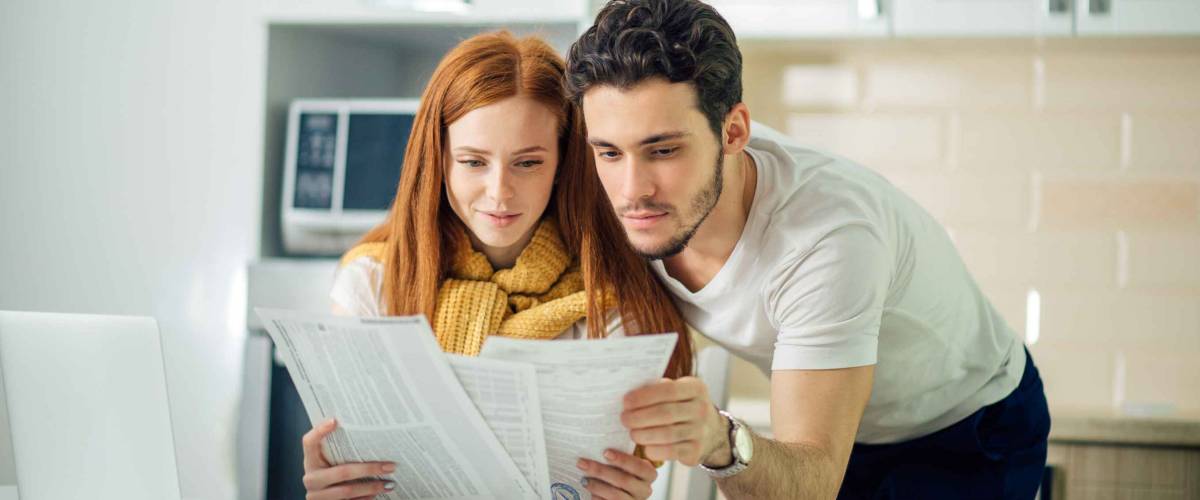 cheerful young couple calculating their bills at home