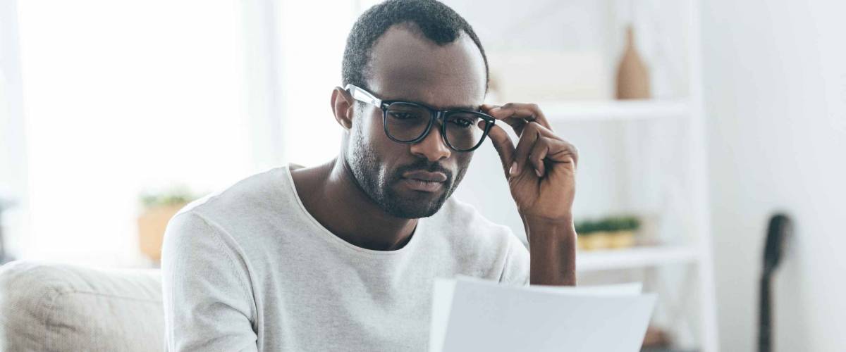Man with glasses sitting on couch, looking at papers