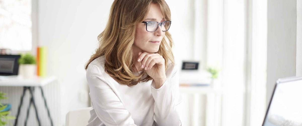 Woman looking at laptop with hand under her chin