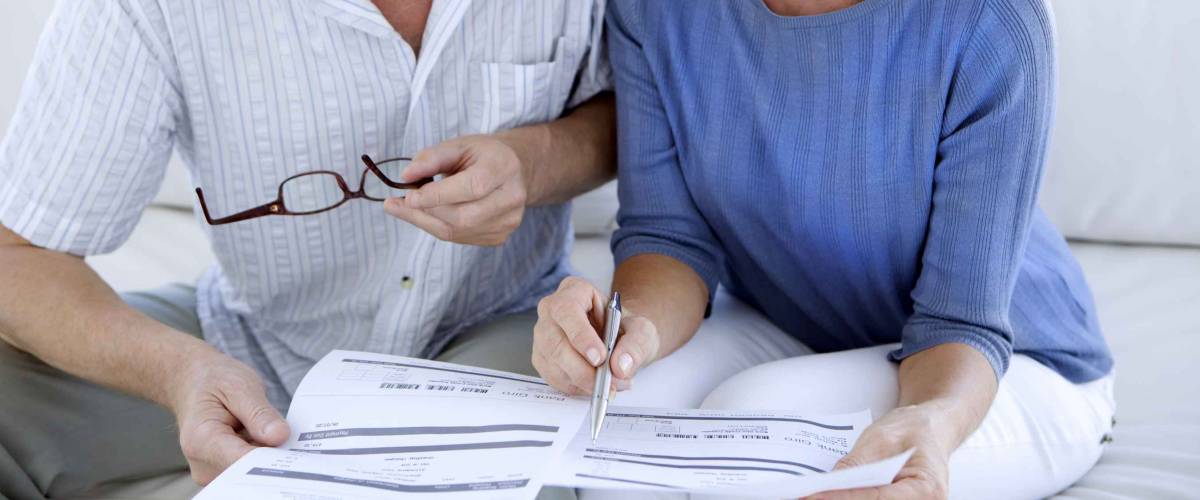 Close up of older couple's hands, looking at piece of paper
