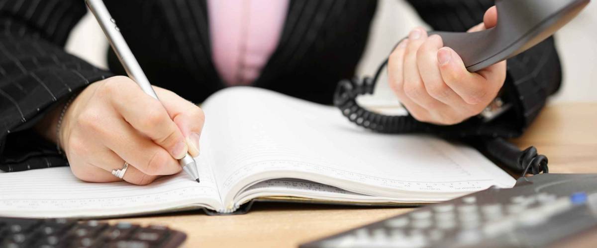 busy secretary is answering call and writing memo at the same time