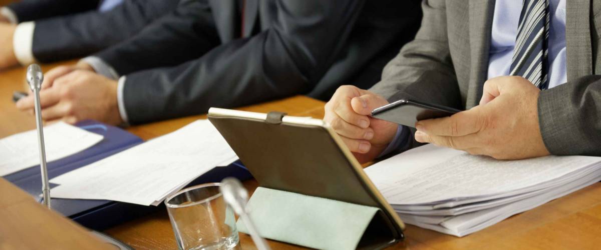 Men in suits and with gadgets during a business meeting. An official, businessman or deputy uses a smartphone and tablet. Close-up.