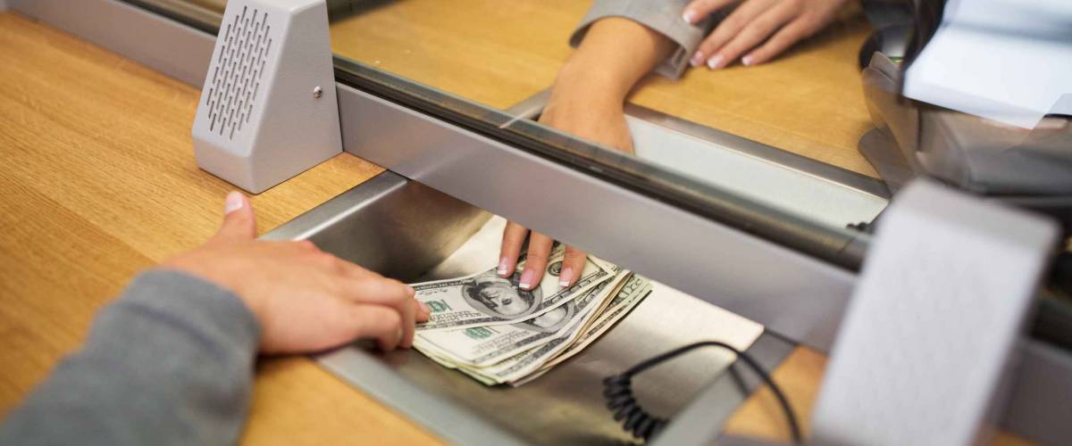 people, withdrawal, saving and finance concept - clerk giving cash money to customer at bank office or currency exchanger