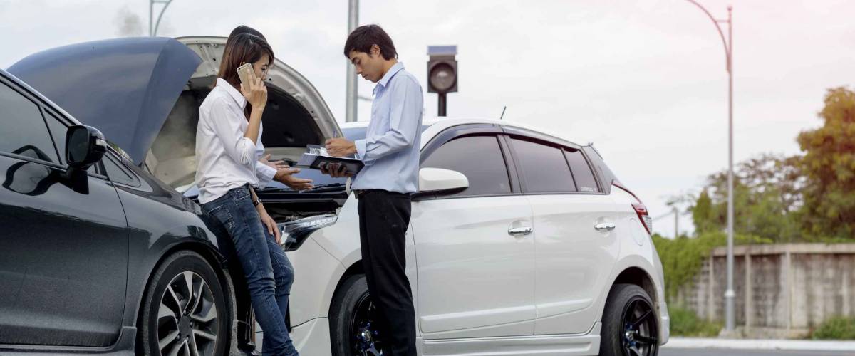 Woman driver calls for instruction during insurance agent review the dammage of the car after accident
