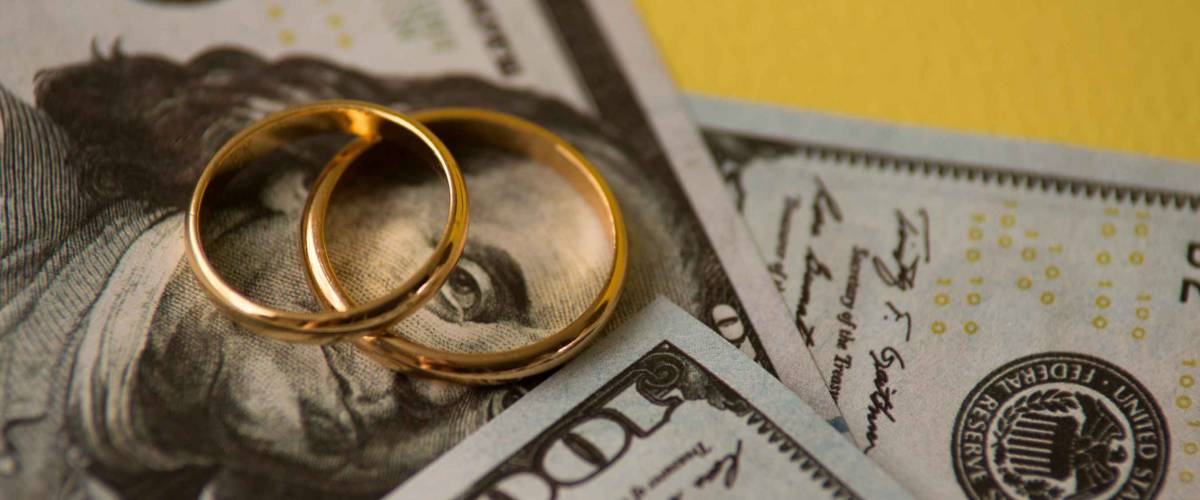 Golden wedding rings on one hundred dollars bill background