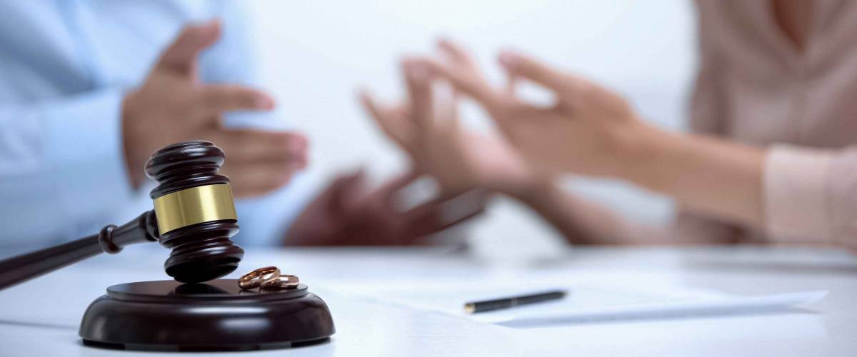 Spouses arguing about property division during divorce, gavel and rings closeup