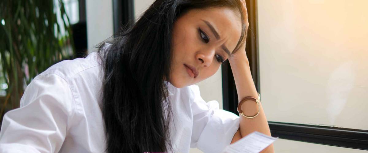 young woman holding papers looking stressed