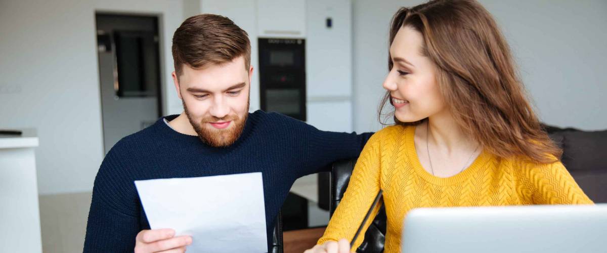 Happy young couple calculating bills at home
