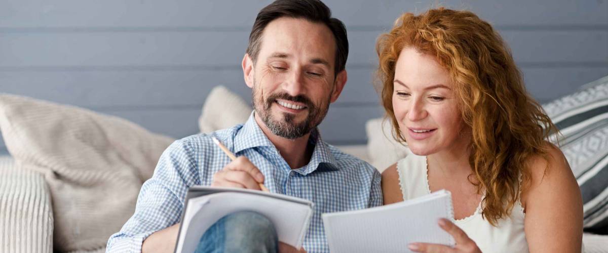 Man and woman looking at papers, making notes while sitting on couch