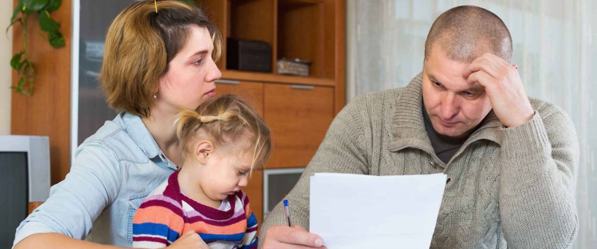 Serious couple with little girl counting budget at home