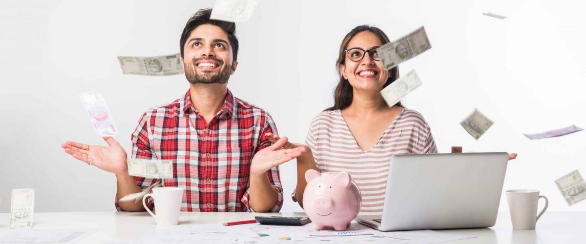 Focused Indian young couple accounting, calculating bills, discussing planning budget together using online banking services and calculator, checking finances