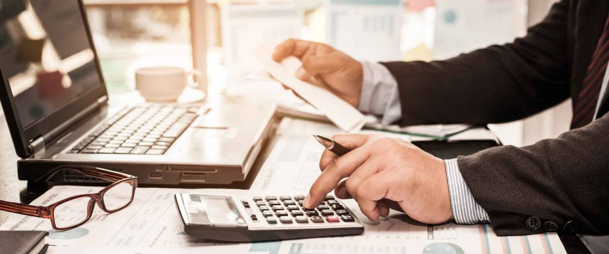 A business man using calculator for calculate expenses bills in his workplace. Business concept.