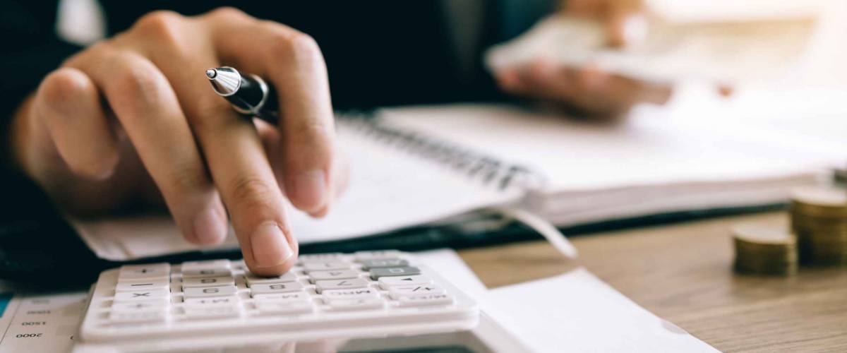 Investors are calculating on calculator investment costs and holding cash notes in hand.